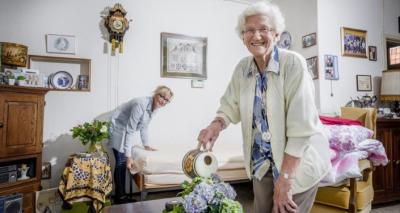 Klant en thuishulp gezamenlijk aan het werk. Mevrouw geeft de plantjes water.