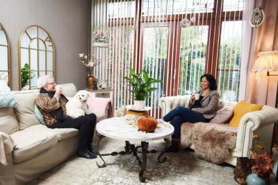 Thuishulp en haar client samen aan de koffie in de huiskamer. Client heeft haar hondje op schoot. Thuishulp en haar client samen aan de koffie in de huiskamer. Client heeft haar hondje op schoot.