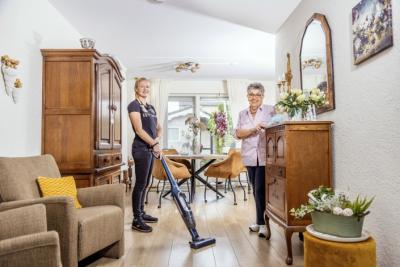 Mevrouw Jannie met haar thuishulp die aan het stofzuigen is.